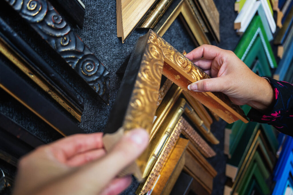 Un artisan encadreur en train de sélectionner une baguette gravée